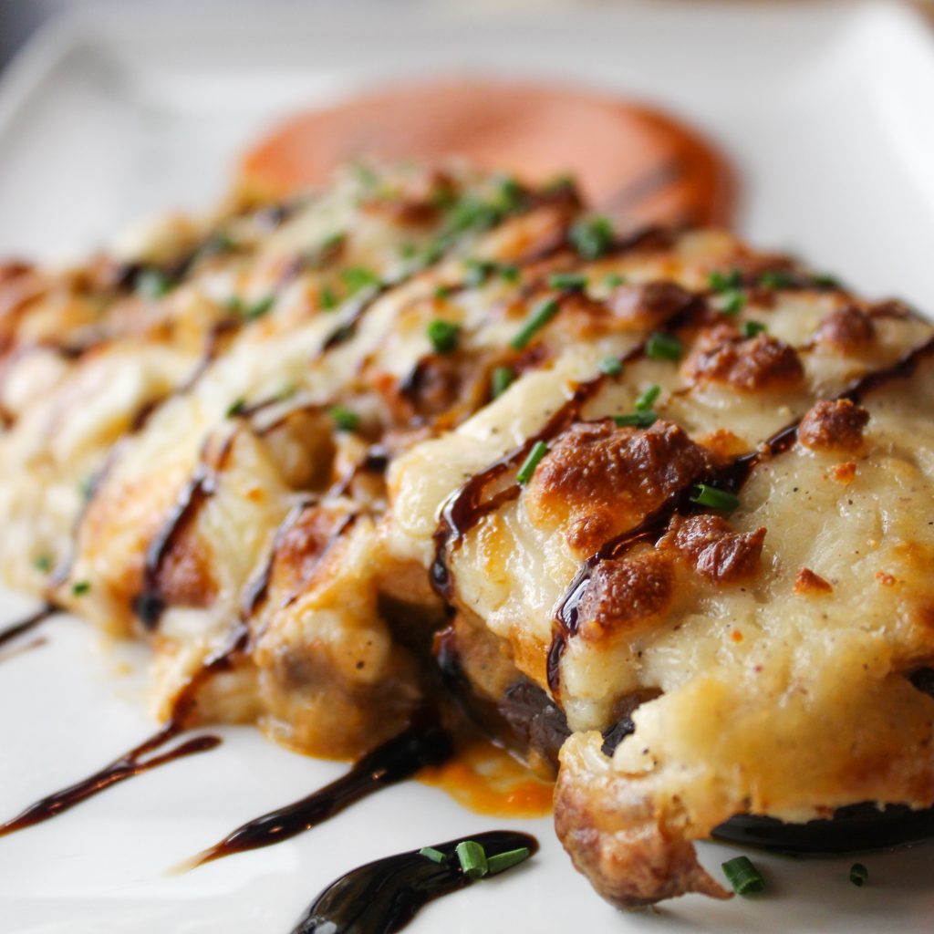 Berenjena rellenada de ternera gratinada acompañada de salsa de tomate casera.