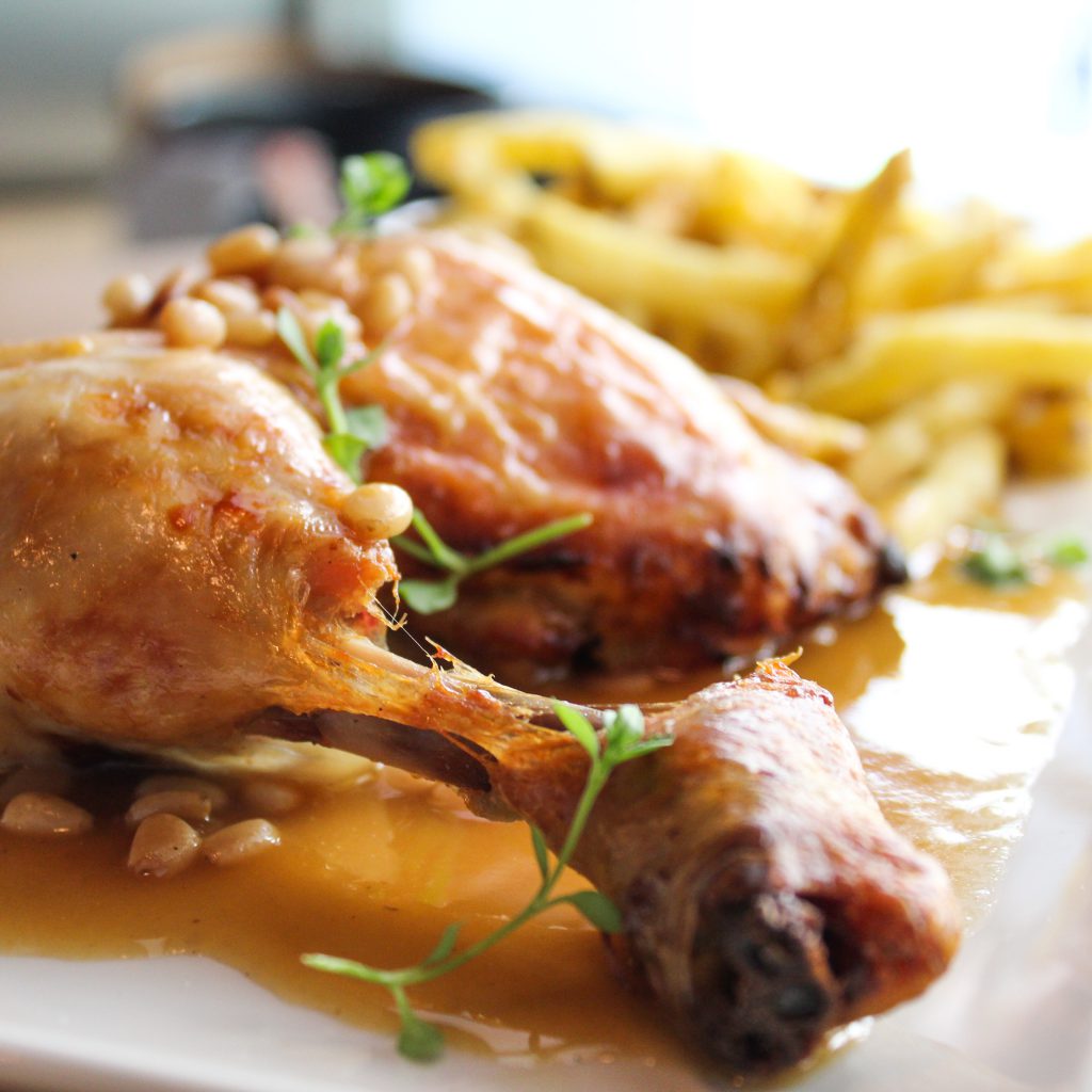 Pollo asado a baja temperatura con salsa de naranja y piñones, servido con patatas fritas