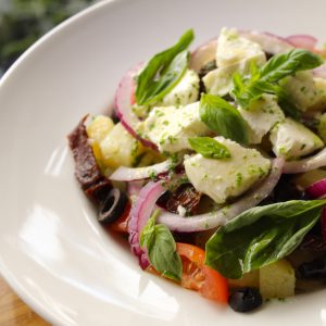 Ensalada de patata, tomate seco, cebolla morada, queso de cabra y albahaca fresca