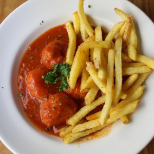 Albóndigas de pollo y espinacas estofadas acompañadas de patatas fritas