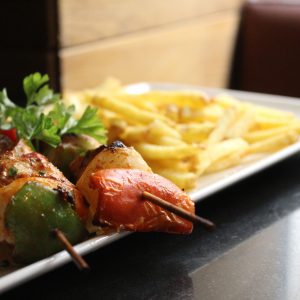 Brocheta de pollo marinado y verduras acompañado de patatas fritas