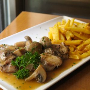 Pollo cocinado en su jugo con salsa de champiñón y patata fritas