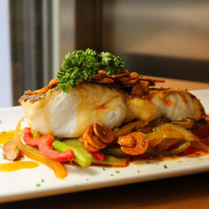 Merluza con verduras de temporada salteadas y refrito de ajo y pimentón